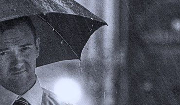 Mężczyzna w deszczu na ulicy, scena reportażowa.